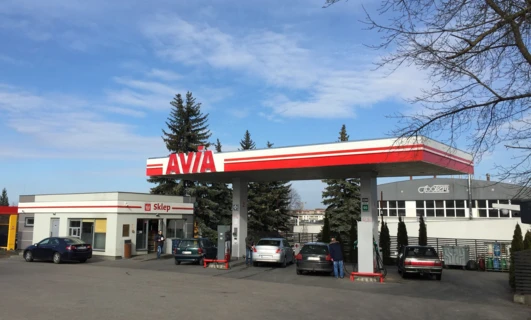 Luksusowy pojazd zaparkowany przy stacji paliw. Znak sklepu AVIA po polsku. Samochód rodzinny tankuje paliwo.