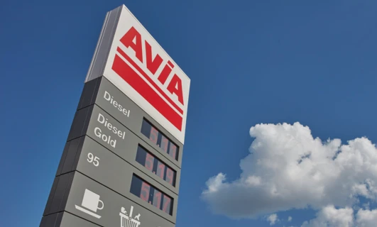 Reklama paliwa diesel AVIA z lusterkiem i zderzakiem samochodowym. Promocja paliwa Gold 95 T w języku polskim.